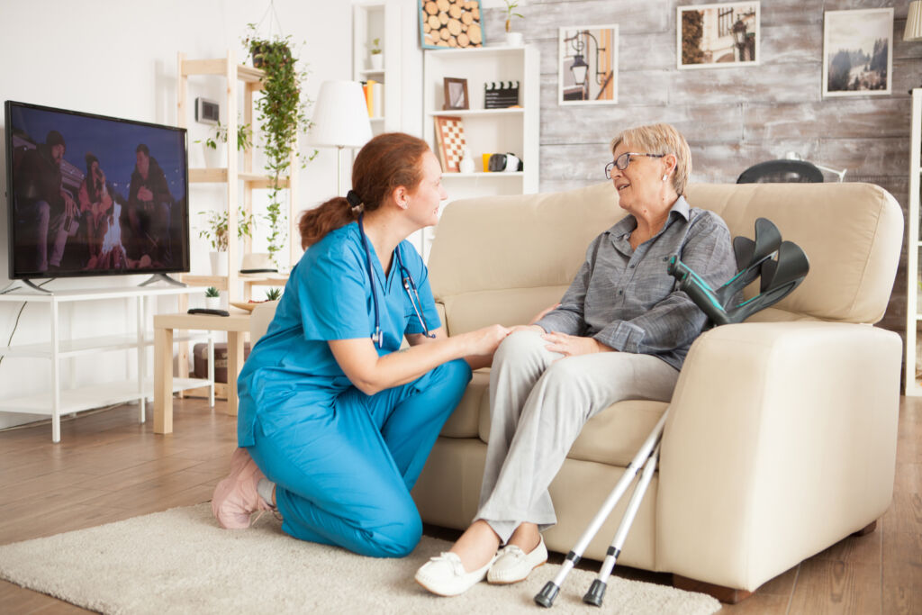 young female nurse wearing blue uniform talking with senior woman in nursing home